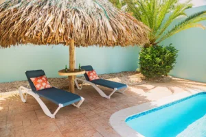 Tropical poolside lounge area at Wayaca Oasis Retreat in Aruba with shaded palapa and relaxing sun chairs